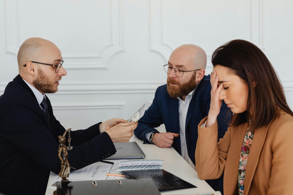 Lawyer discussing divorce settlement with distressed couple during tense meeting.
